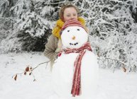Caucasian happy girl making snowman outdoors — Stock Photo