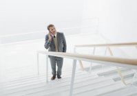 Uomo d'affari che parla al cellulare alla base delle scale — Foto stock