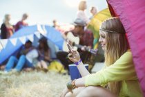Mulher mensagens de texto com telefone celular na barraca no festival de música — Fotografia de Stock