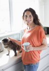Счастливая женщина кормит милую кошку на кухне — стоковое фото