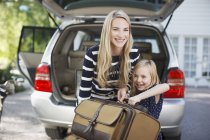 Mutter und Tochter tragen Gepäck zum Auto — Stockfoto