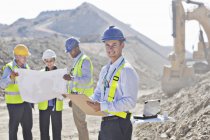 Businessmen reading blueprints in quarry — Stock Photo