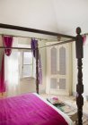Quatro cama de cartaz com cama roxa no quarto — Fotografia de Stock