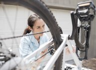 Skillful caucasian woman working on bicycle in driveway — Stock Photo