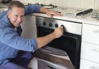 Skillful caucasian electrician working on oven in kitchen — Stock Photo