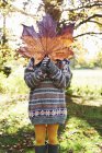 Girl playing with autumn leaf outdoors — Stock Photo
