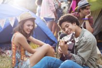 Man playing guitar outside tents at music festival — Stock Photo