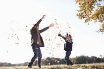 Padre e hijo jugando en hojas de otoño - foto de stock