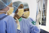 Chirurgen untersuchen Röntgenbilder im Operationssaal — Stockfoto