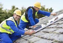 Працівники встановлюють сонячні панелі на даху — стокове фото