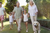 Family walking together in park with dog — Stock Photo