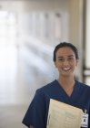 Медсестра посміхається в сучасному лікарняному коридорі — стокове фото