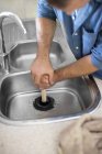 Искусный кавказский сантехник расчищает кухонную раковину — стоковое фото