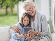 Mujer y nieta usando tableta digital - foto de stock