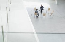 Бизнесмены встречаются в кругу стульев в холле — стоковое фото