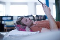 Людина використовує цифровий планшет на ліжку — стокове фото