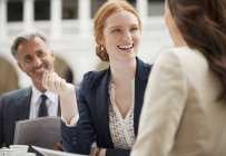 Smiling business people meeting at sidewalk cafe — Stock Photo