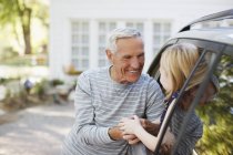Пожилой мужчина приветствует внучку в окне машины — стоковое фото