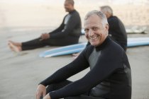 Older surfers sitting on boards on beach — Stock Photo