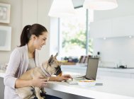 Frau benutzt Laptop mit Hund auf Schoß — Stockfoto