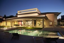 Casa de lujo y piscina iluminadas por la noche - foto de stock