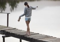 Mujer caminando por el muelle sobre el lago - foto de stock