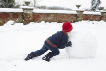 Білий щасливий хлопчик робить сніговика на відкритому повітрі — стокове фото