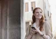 Усміхнена жінка тримає мобільний телефон — стокове фото