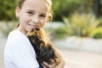 Smiling girl holding guinea pig outdoors — Stock Photo