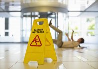 Businessman slipping on wet office floor — Stock Photo