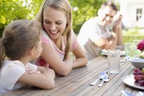 Happy family sitting at table outdoors — Stock Photo