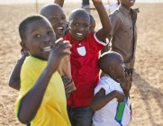 Chicos africanos jugando juntos en el campo de tierra - foto de stock