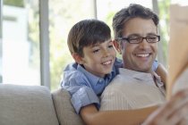 Father and son hugging on sofa — Stock Photo