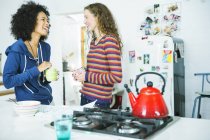 Mulheres felizes jovens falando na cozinha — Fotografia de Stock