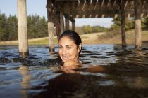 Портрет усміхненої жінки, що плаває в озері під причалом — стокове фото