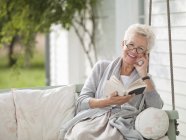 Woman reading in porch swing — Stock Photo