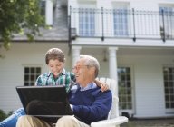 Man using laptop with granddaughter outdoors — Stock Photo