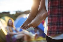 Man carrying barefoot woman outside tents at music festival — Stock Photo