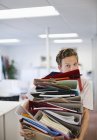 Бизнесмен балансирует папки в современном офисе — стоковое фото