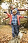 Uomo e nipote che giocano sul log in park — Foto stock