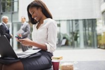 Бізнес-леді сидить на лавці за допомогою мобільного телефону — стокове фото
