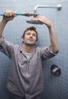 Klempner arbeitet an Duschkopf im Badezimmer — Stockfoto