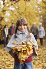 Усміхнена дівчина грає в осінньому листі — стокове фото