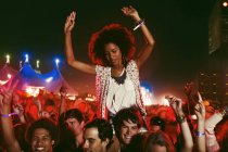 Cheering woman on man?s shoulders at music festival — Stock Photo