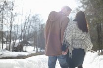Пара держащихся за руки и идущих по снежной полосе — стоковое фото