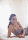 Portrait of smiling woman in nightgown laying on bed — Stock Photo