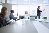 Businesswoman at flipchart leading meeting in conference room at modern office — Stock Photo