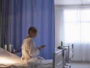 Пациент с помощью мобильного телефона на больничной койке — стоковое фото