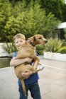 Sorrindo menino segurando cão ao ar livre — Fotografia de Stock