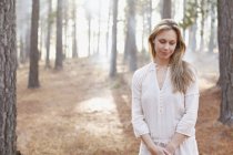 Portrait of serene woman in sunny woods — Stock Photo